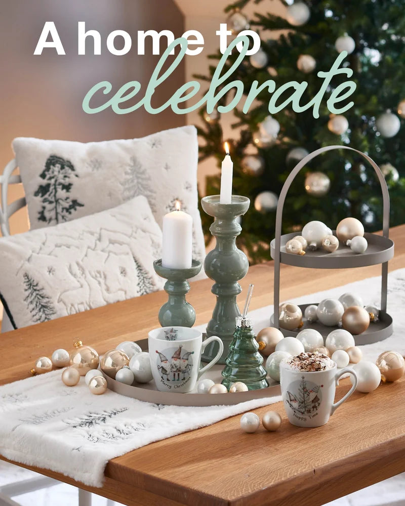 Festlich gedeckter Tisch mit Kerzen, Tassen und Christbaumkugeln