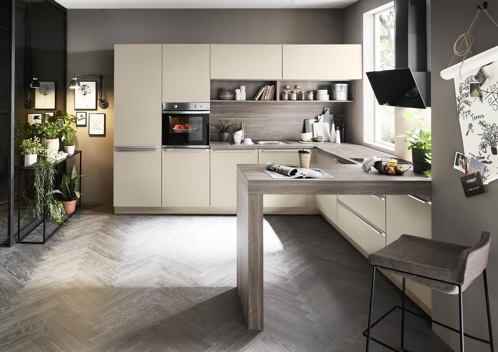 Moderne Nolte Küche in U-Form mit sandfarbenen Fronten, Thekenlösung und Rückwand in Beige