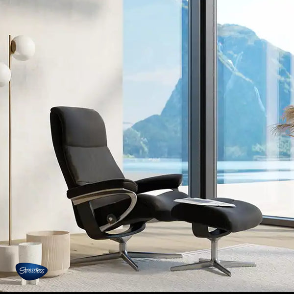 Stressless Sessel in schwarzem Bezug vor Panoramafenster mit Ausblick